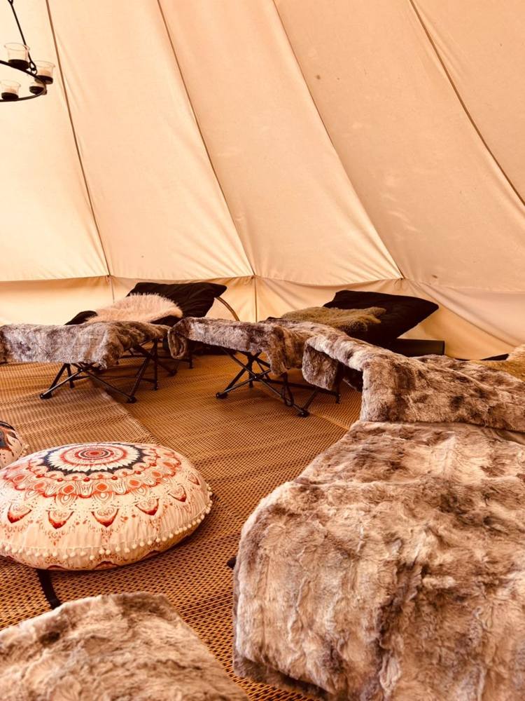 Inside the bell tent: cosy loungers with faux-fur throws and floor cushions.