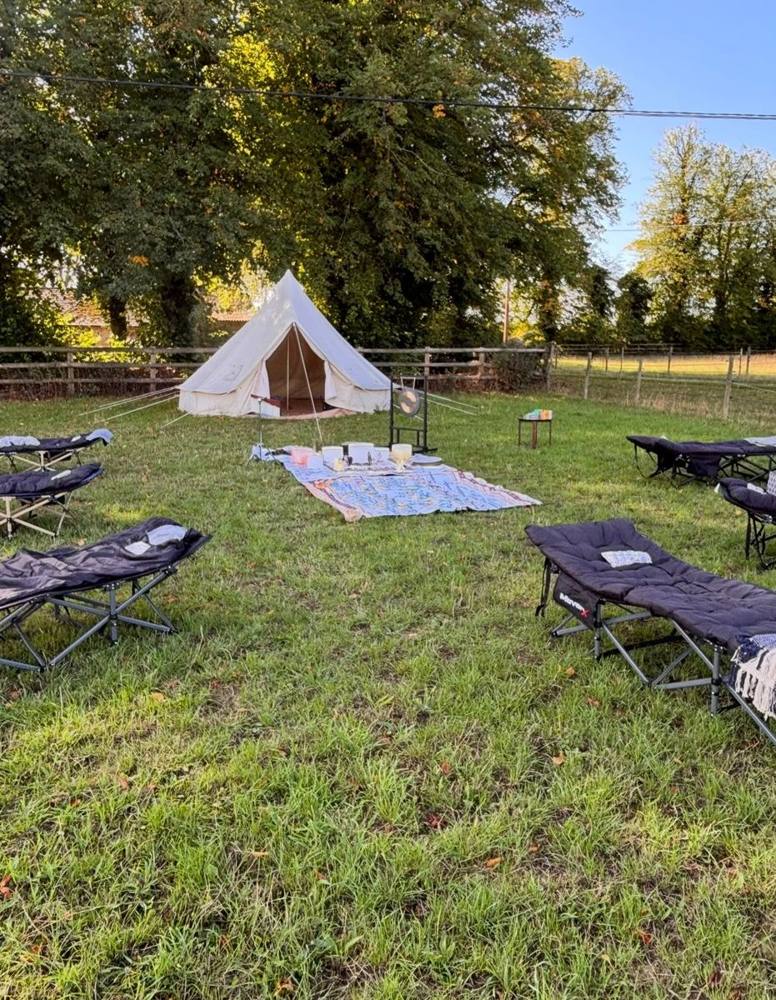 Loungers arranged on the grass around crystal bowls, with a bell tent behind.