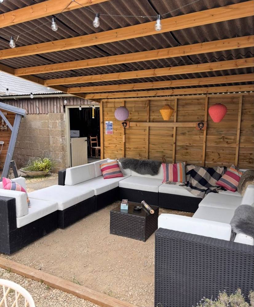 A covered outdoor lounge with sofas, cushions and festoon lights.