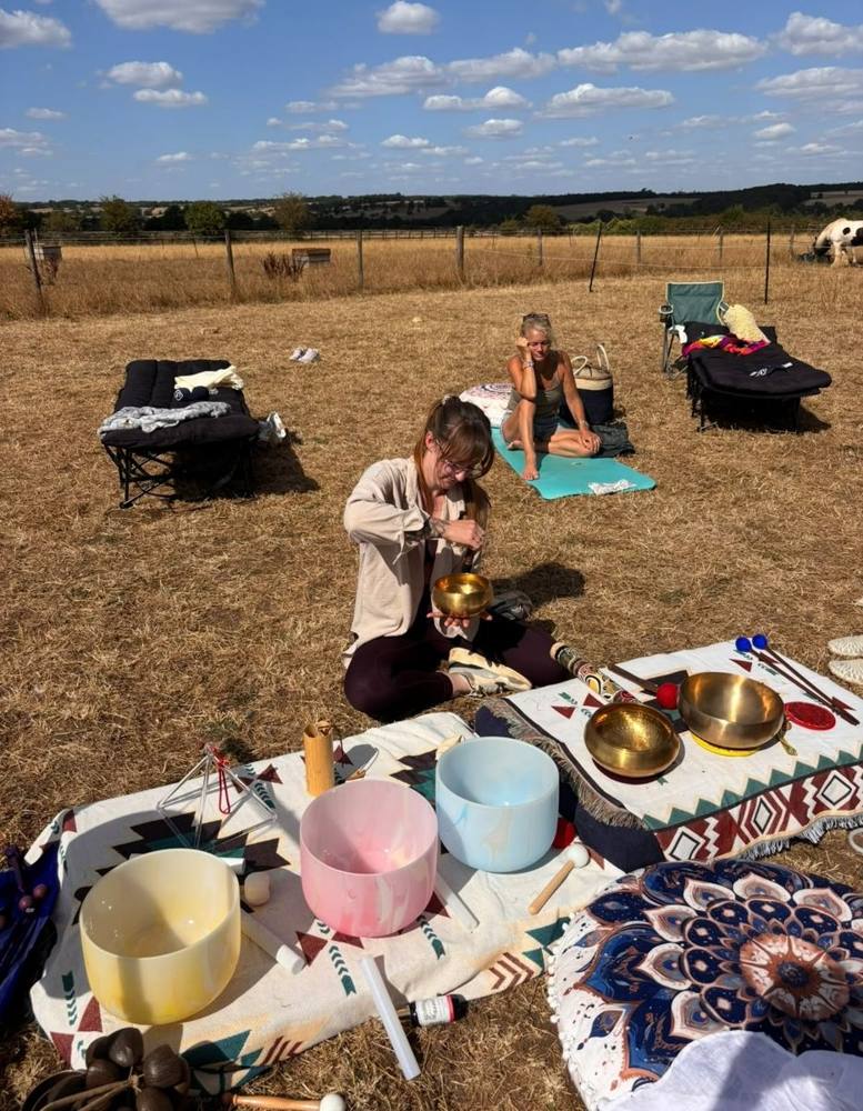 A group soundbath in the field, with crystal bowls and loungers in the sunshine.